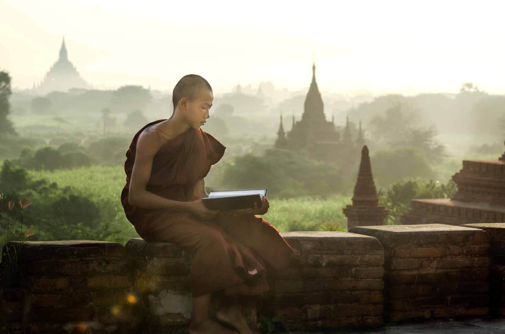 A monk reading at sunrise in Bagan - not using social media