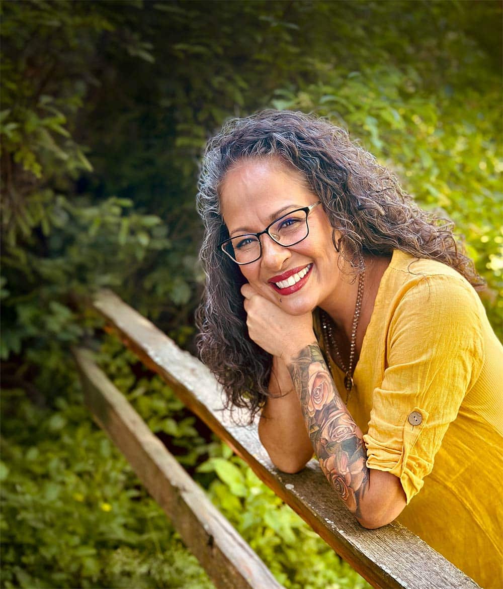 Tracy Douglas, MS, LPC, founder of Your GenX Therapist, smiling while leaning on a wooden railing